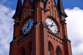 Beautiful, brick church steeple with clock, at blue sky with white clouds on background, in Sundsvall, Sweden