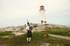Man near the beautiful white and red lighthouse in Peggy's Cove, Nova Scotia, Scotland