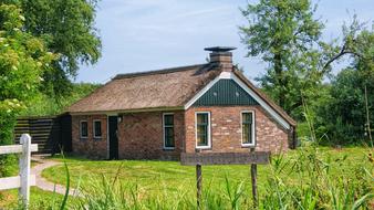 Colorful and beautiful farm cottage, among the green plants, in Netherlands