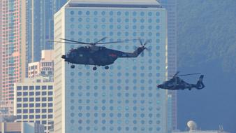 Flying army helicopters, among the buildings in Hong Kong