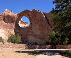 Beautiful Navajo window rock, among the green trees, at blue sky on background, in New Mexico, America