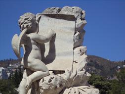 Beautiful statue of the Angel, on the cemetery, on the colorful mountains, at blue sky on background