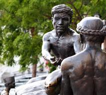 Beautiful bronze sculpture of the people, near the green trees