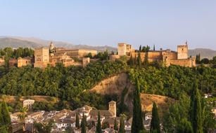 Beautiful and colorful Alhambra Palace, among the green plants, on the mountain in Granada, Spain