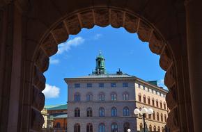 Colorful buildings, on the view from the archway, at blue sky with white clouds on background