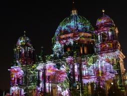 Beautiful building, in the colorful lights with the flowers, in Berlin, Germany, in the evening