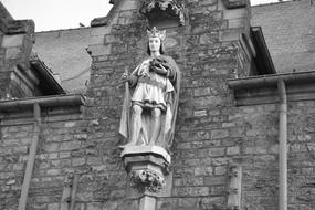 black and white, sculpture of Saint Louis on the background of the facade of a brick building in France