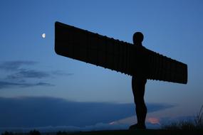 sculpture of an angel at the top of the hill in the evening