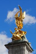 Beautiful, shiny, golden Queen Victoria Monument, at blue sky with white clouds on background, in London, England, United Kingdom