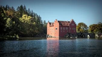 Beautiful castle, among the colorful plants, on the shore of the lake in Czech Repbublic