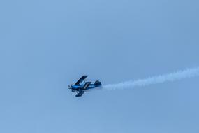 Beautiful, flying Pitts S2a with white contrail, at blue sky on background, on Flight Days Soest 2017