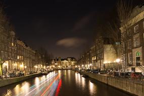 Beautiful canal with colorful lights, in motion, in Amsterdam, Netherlands, at the night