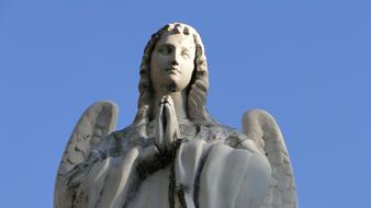 stone sculpture of a woman angel on a blue sky background