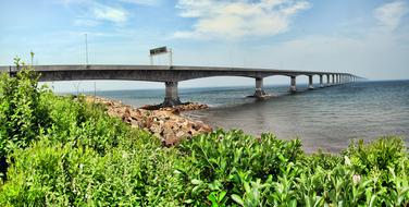 Long Confederation Bridge in Brunswick, Canada, view from the shore with green plants