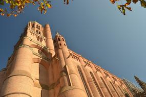 Beautiful cathedral in Albi, France, among the colorful trees, under the blue sky