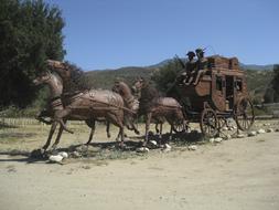 Beautiful statue of the horses, with the wagon, on the colorful hills, at blue sky on background