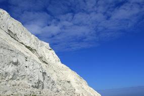 Beautiful, rocky beach of the Beachy Head in Britain, under the blue sky with white clouds