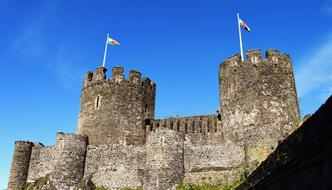 Beautiful castle with the plants and flags, in Wales, under the blue sky with white clouds