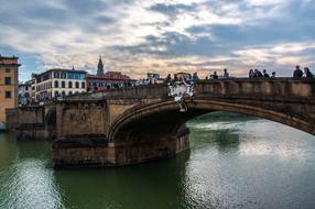 Beautiful landscape of Florence, Tuscany, Italy, with buildings and bridge above the water, at colorful and beautiful sunset with clouds