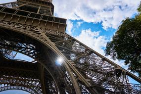 sun beams bursting through Eiffel Tower metal construction, France, Paris