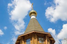 Beautiful and colorful steeple of the church with the cross, in Russia, under the blue sky with white clouds