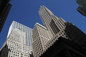 Skyscraper, among the other buildings in Manhattan, New York, USA, with the windows, in sunlight and shadows, under the blue sky