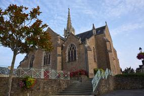 Beautiful church in Ãpiniac, Britain, France, among the plants, under the blue sky with white clouds