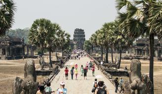 People walking on the alley, among the beautiful temple with colorful palm trees