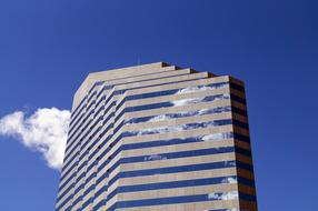 Shiny skyscraper with reflections of the blue sky with white clouds