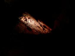 Close-up of the colorful stone in the cave, in light, among the darkness