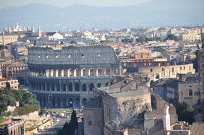 Beautiful landscape with the Colosseum, among the colorful plants in Rome, Italy, near the mountains