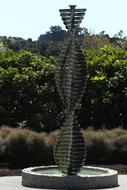 Monument in the garden with beautiful and colorful plants, in sunlight