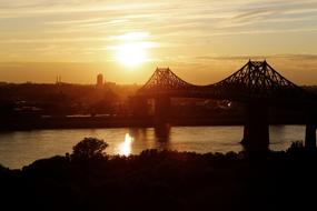 Beautiful landscape with the silhouettes of the suspension bridge and buildings, at colorful and beautiful dusk