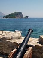 Cannon at the wall near the green island, among the beautiful, turquoie water