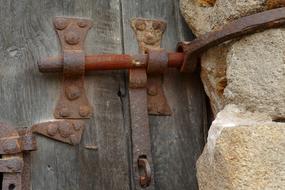 Close-up of the old, rusty lock on the wooden door in the stone wall