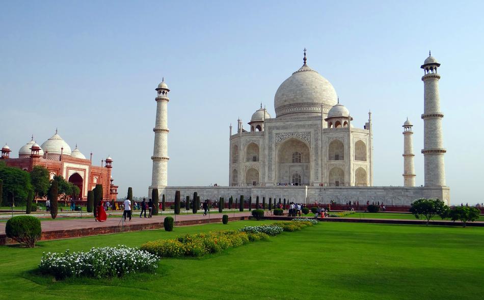 People, near the beautiful Taj Mahal, among the green fields in Agra, India