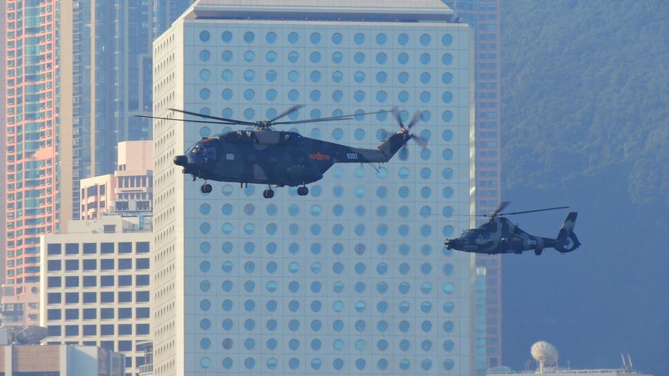 Flying army helicopters, among the buildings in Hong Kong