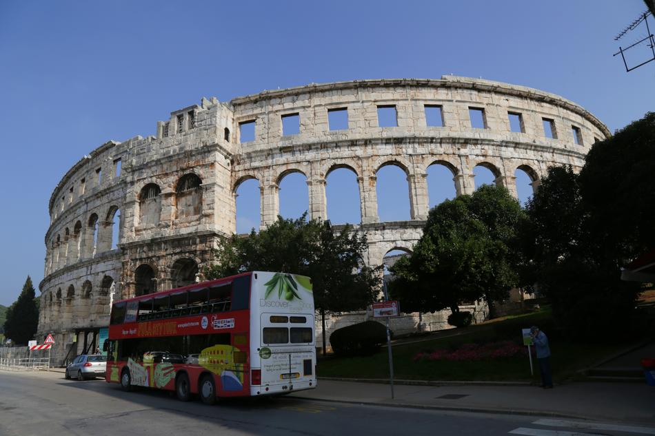 Bus, near the beautiful arena in Pula, Croatia, among the green trees
