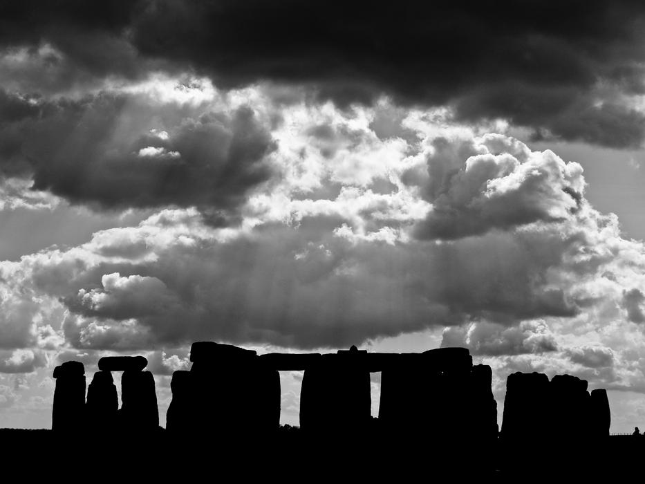 Black and white photo with the silhouettes of the beautiful Stonehenge, in Salisbury, England, under the cloudy sky