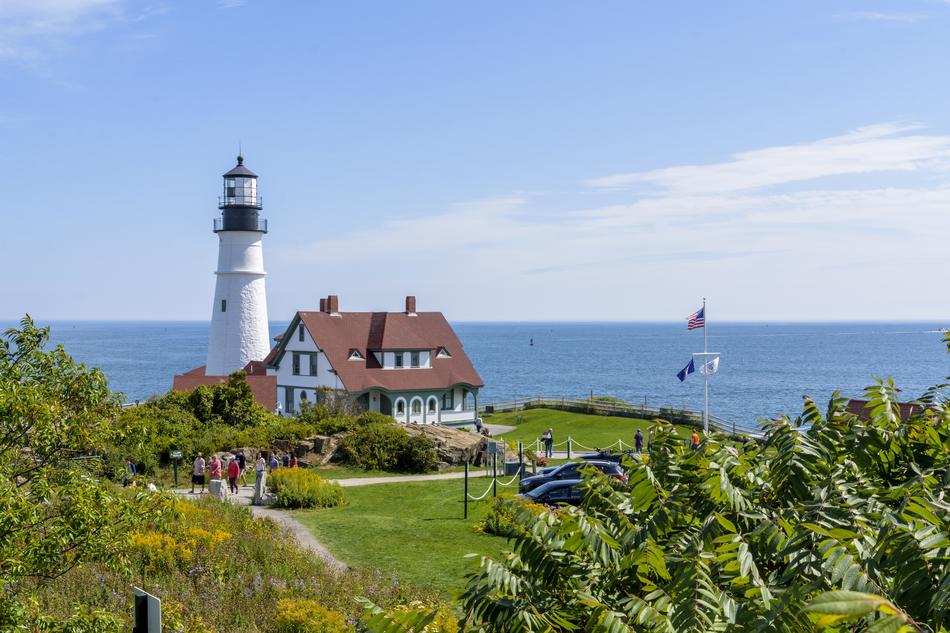 Beautiful landscape with the lighthouse and house, among the colorful plants on the coast