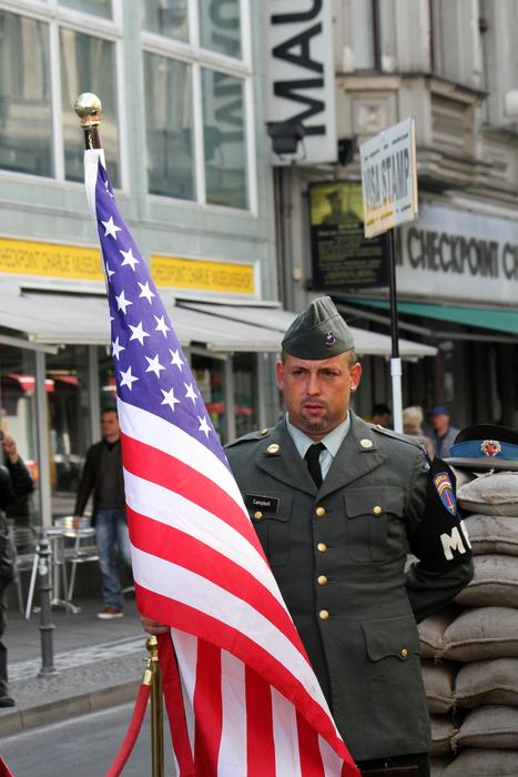 Soldier with the flag of USA, at the checkpoint in Berlin, Germany