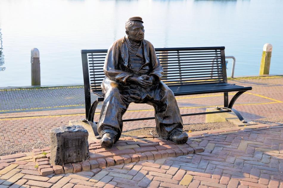 statue of a fisherman sitting on a bench in the netherlands