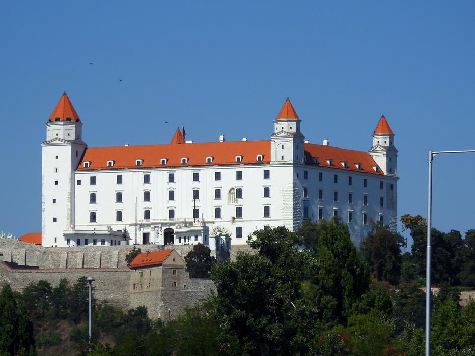Beautiful, white and orange castle in Bratislava, Slovakia, among the green trees, under the blue sky