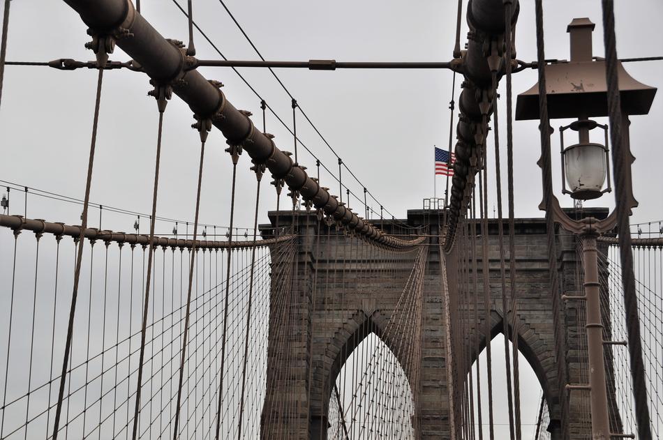 Beautiful Brooklyn Bridge with the flag of USA, in New York, USA, under the clouds