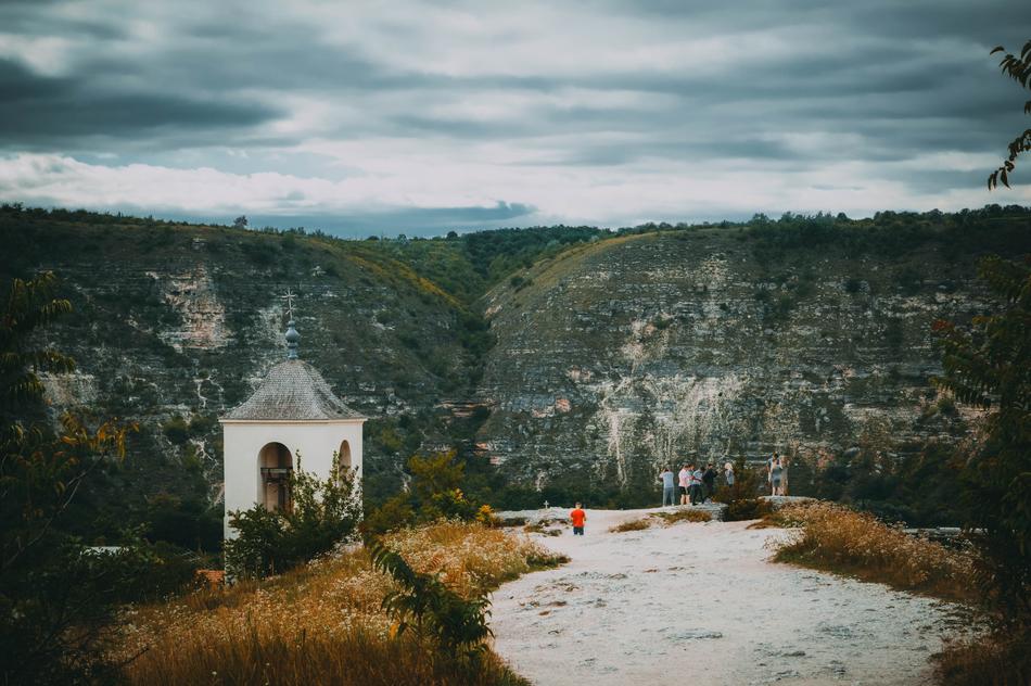 People near the beautiful landscape with the chapel on the colorful mountains, in the autumn