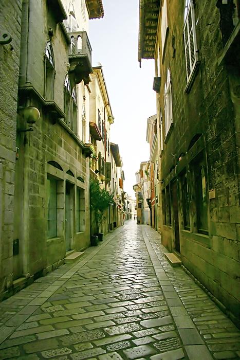 Beautiful, old street with pavement in sunlight, among the buildings