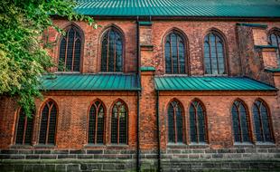 Beautiful facade of the brick building with green roof, near the colorful tree