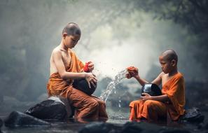 two young buddhist monks washing pots with Water