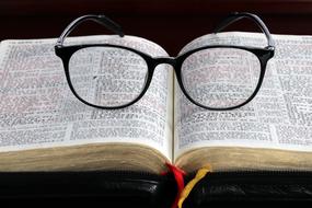 Glasses in black frame on open Bible