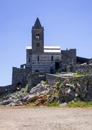 Beautiful landscape of the church with the steeple, on the hill with green plants, at blue sky in Italy